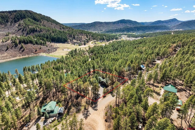 drone / aerial view featuring a water and mountain view and a wooded view