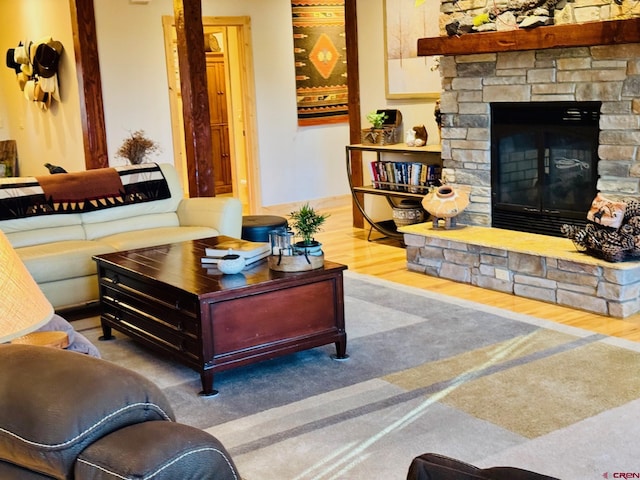 living room with a stone fireplace and wood finished floors