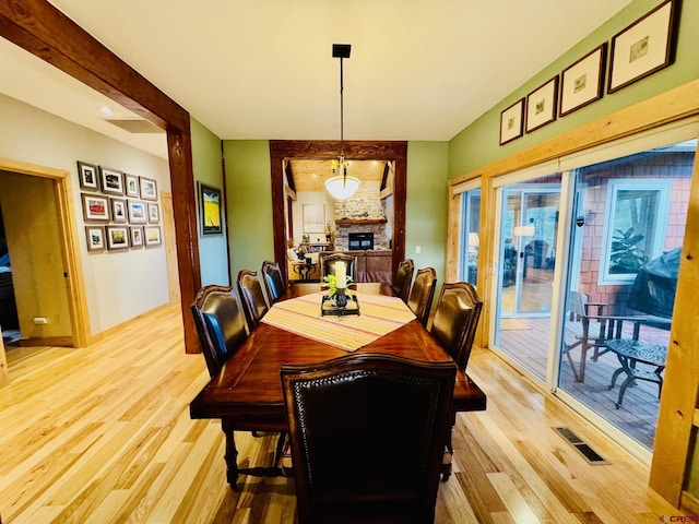 dining room featuring visible vents, a stone fireplace, and light wood-type flooring