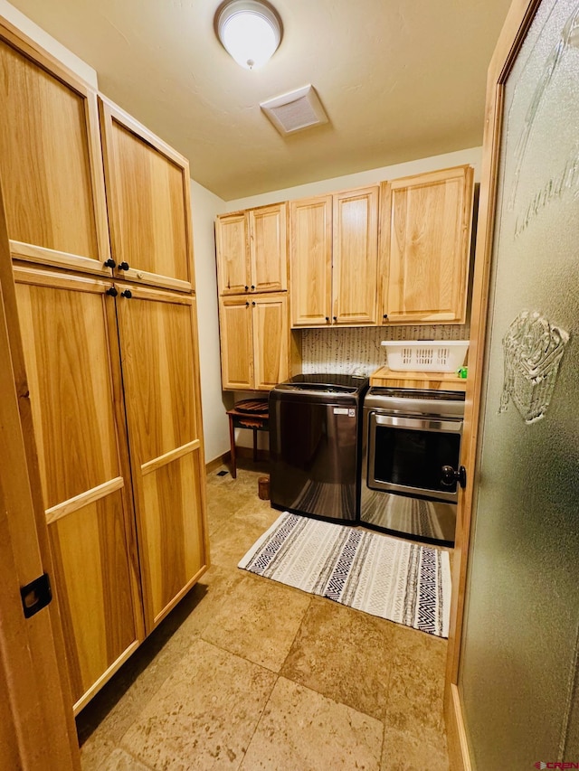 washroom featuring visible vents, cabinet space, and washer and clothes dryer