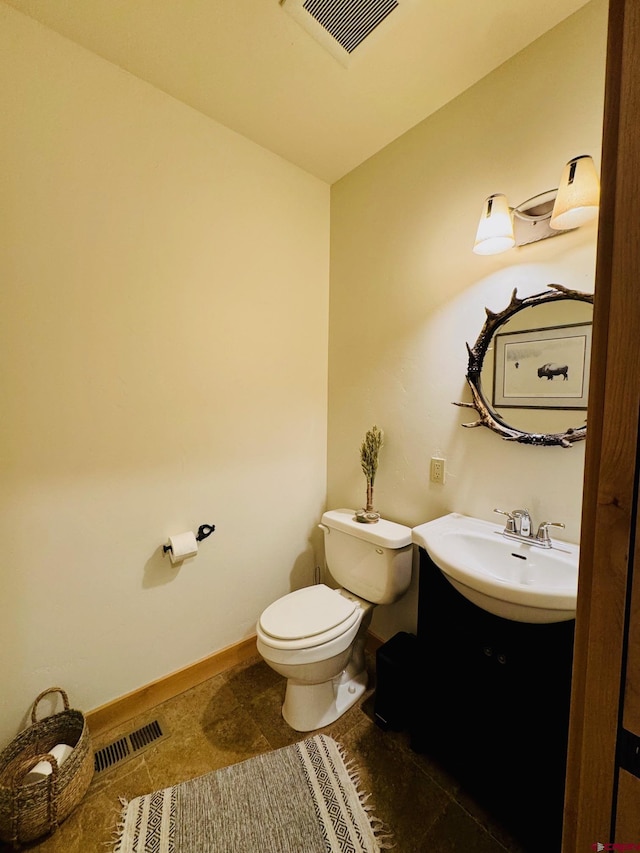 half bathroom featuring visible vents, a sink, baseboards, and toilet