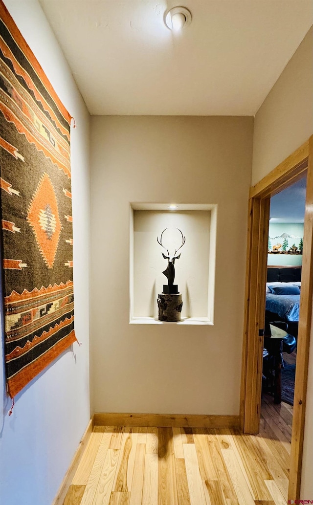 corridor featuring baseboards and wood finished floors