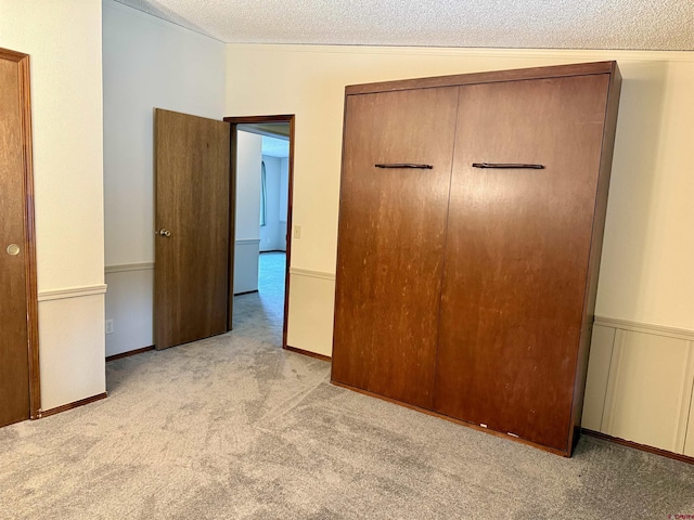 unfurnished bedroom featuring carpet flooring, a textured ceiling, and a closet