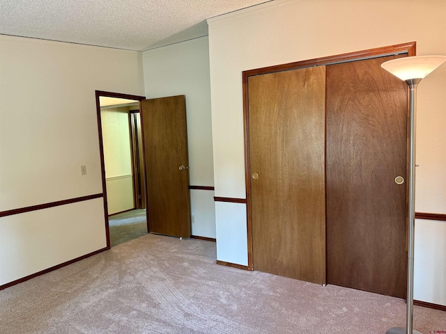 unfurnished bedroom with a closet, carpet flooring, a textured ceiling, and baseboards