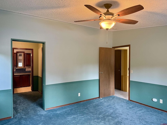 unfurnished room featuring a textured ceiling, ceiling fan, and dark colored carpet