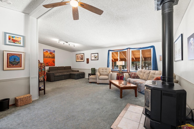 carpeted living room featuring ceiling fan, a wood stove, and a textured ceiling