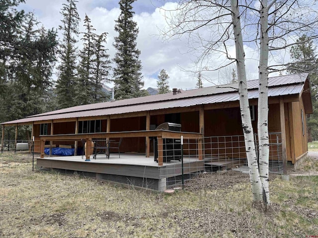 back of property featuring an exterior structure, metal roof, and an outdoor structure