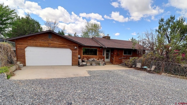 view of front of home featuring fence, an attached garage, entry steps, a chimney, and driveway