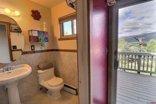 half bathroom featuring wainscoting, toilet, tile patterned floors, tile walls, and a baseboard radiator