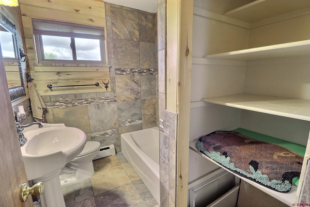 bathroom featuring toilet, stone finish flooring, and a bath