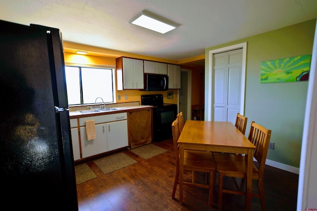 kitchen featuring a sink, black appliances, and dark wood finished floors