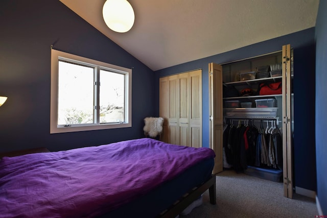 bedroom featuring vaulted ceiling, two closets, and carpet flooring