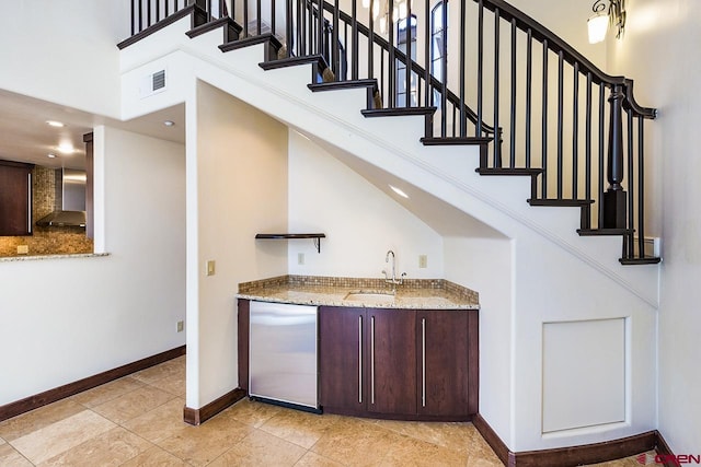 bar with wet bar, visible vents, a sink, baseboards, and stainless steel fridge