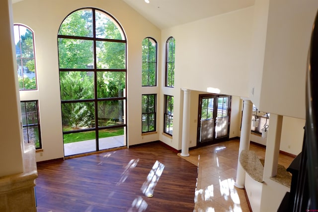 doorway with baseboards, decorative columns, high vaulted ceiling, and french doors