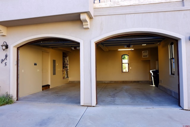 doorway to property with a garage, stucco siding, driveway, and electric panel