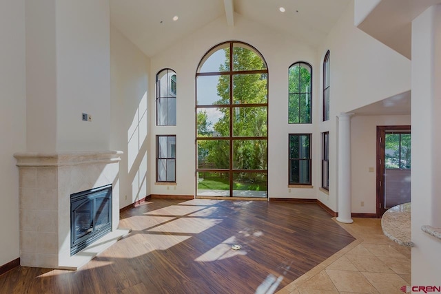 unfurnished living room with beamed ceiling, high vaulted ceiling, plenty of natural light, and a fireplace