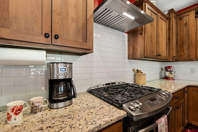 300 Copper Rim Trl, Durango, CO 81301 - kitchen with brown cabinets, light stone countertops, stainless steel range with gas stovetop, wall chimney exhaust hood, and backsplash