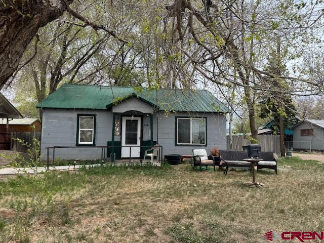 ranch-style home with a front lawn, fence, and metal roof