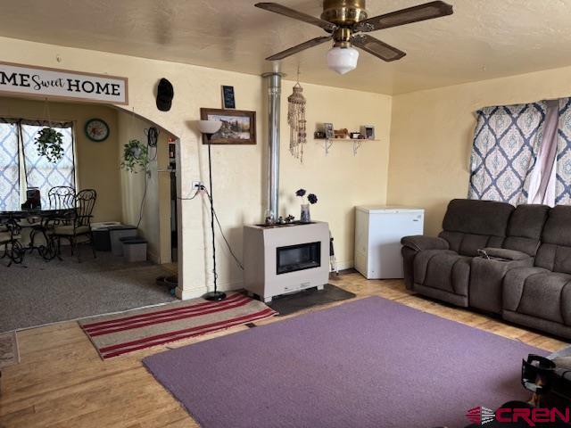living room with arched walkways, ceiling fan, and wood finished floors