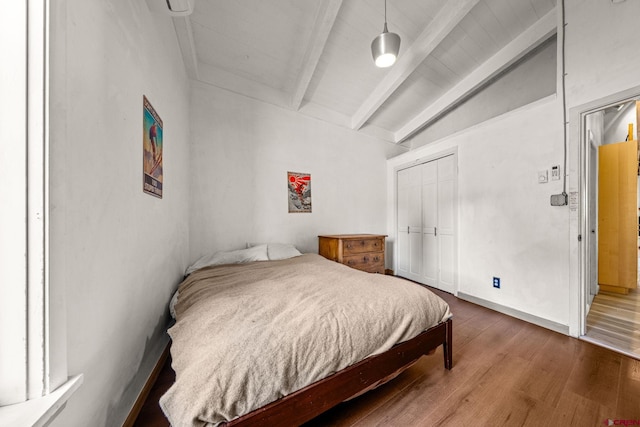 bedroom featuring vaulted ceiling with beams, a closet, and wood finished floors