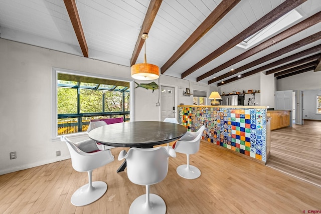 dining area featuring baseboards, lofted ceiling with beams, and wood finished floors