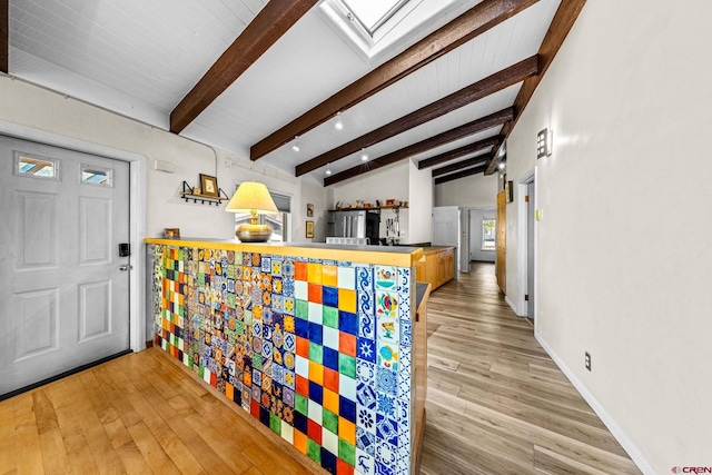 entryway featuring baseboards, lofted ceiling with beams, and wood finished floors