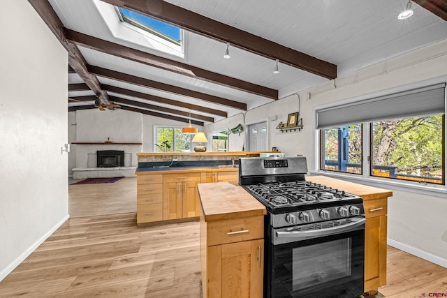 kitchen featuring butcher block counters, baseboards, open floor plan, light wood-style floors, and stainless steel gas range