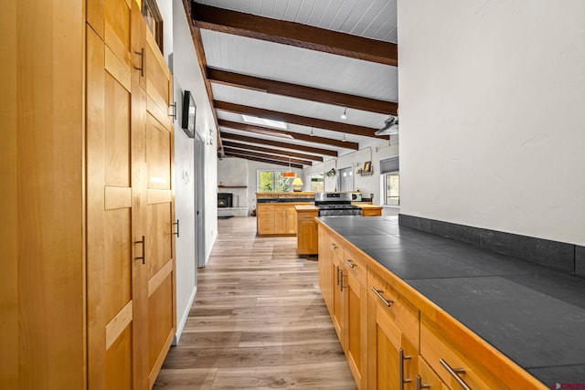 kitchen featuring vaulted ceiling with beams, tile countertops, light wood-style flooring, and gas range