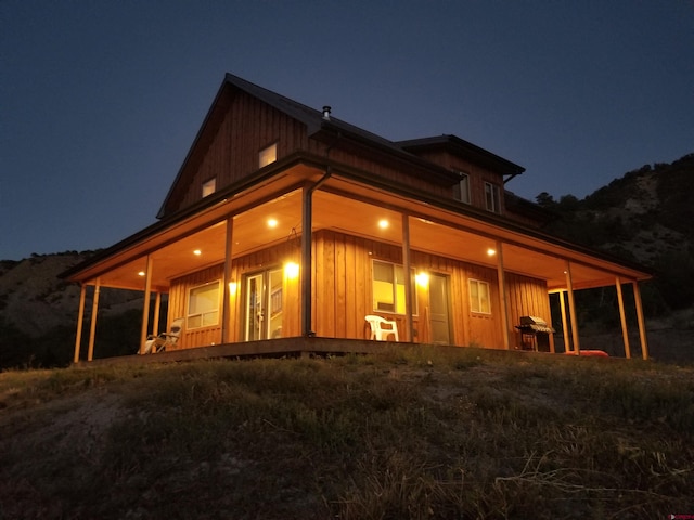 back of house at night featuring board and batten siding