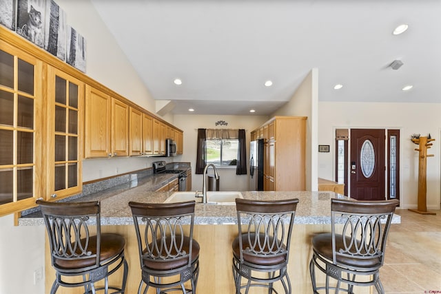 kitchen with a kitchen bar, a sink, glass insert cabinets, stainless steel appliances, and recessed lighting