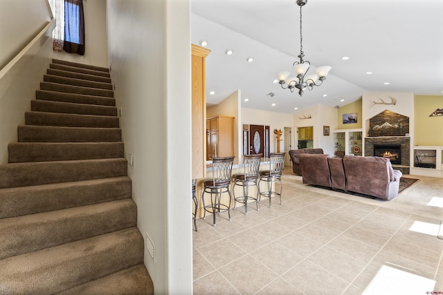 staircase with tile patterned flooring, a lit fireplace, recessed lighting, a notable chandelier, and vaulted ceiling