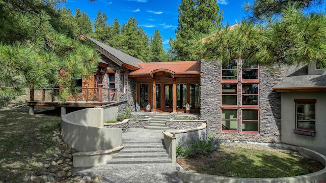 back of house featuring french doors, metal roof, and stone siding