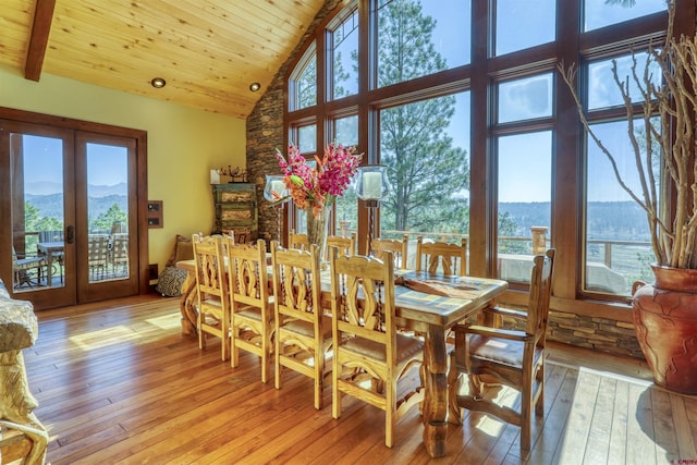dining area with high vaulted ceiling, a mountain view, french doors, and light wood-style flooring