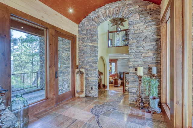 foyer with arched walkways, ornate columns, and stone tile flooring