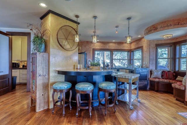 bar with black microwave, a sink, light wood-style flooring, recessed lighting, and decorative light fixtures