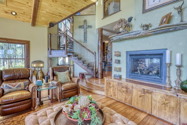 living room featuring wood-type flooring, high vaulted ceiling, stairs, wooden ceiling, and beamed ceiling
