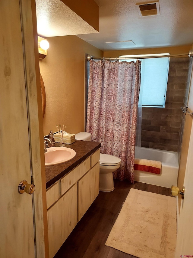 bathroom with vanity, toilet, shower / bathtub combination with curtain, wood finished floors, and visible vents