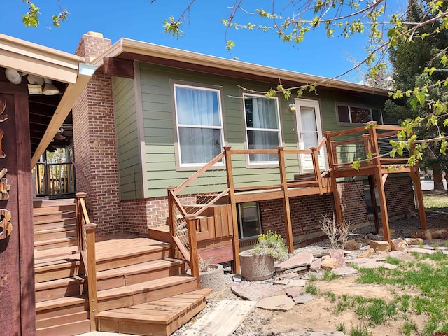 rear view of property featuring stairs, a wooden deck, and a chimney
