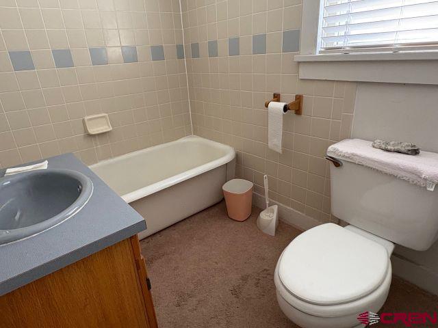 231 3rd Ave, Ouray, CO 81427 - full bathroom featuring a bathing tub, vanity, toilet, and tile walls