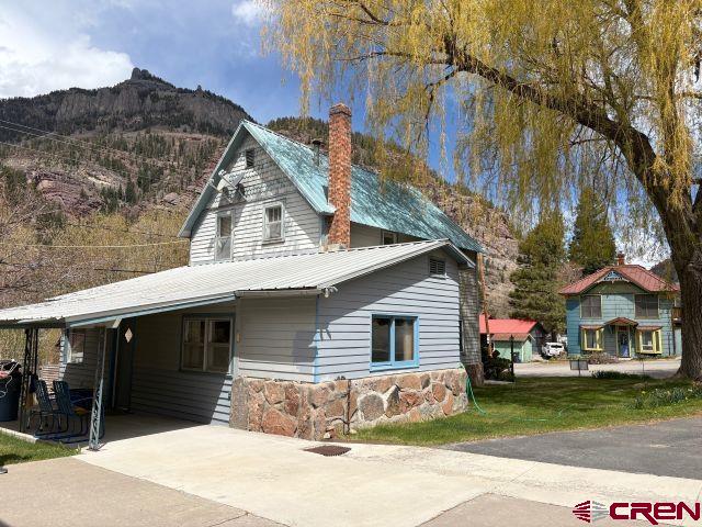 231 3rd Ave, Ouray, CO 81427 - view of front of house featuring a chimney, metal roof, a mountain view, driveway, and a carport