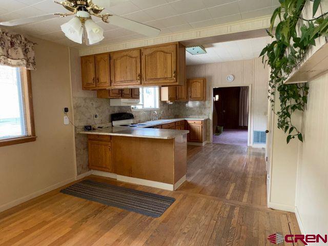 231 3rd Ave, Ouray, CO 81427 - kitchen featuring brown cabinets, light wood finished floors, light countertops, range, and a peninsula