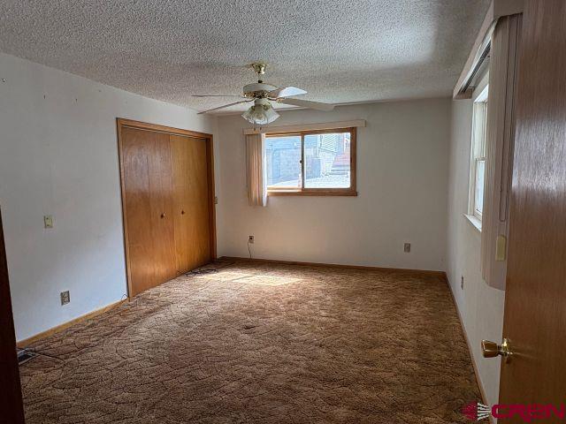 231 3rd Ave, Ouray, CO 81427 - unfurnished bedroom featuring carpet flooring, a ceiling fan, a textured ceiling, and a closet