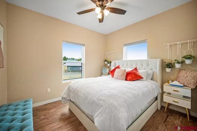 bedroom featuring a ceiling fan, baseboards, multiple windows, and wood finished floors