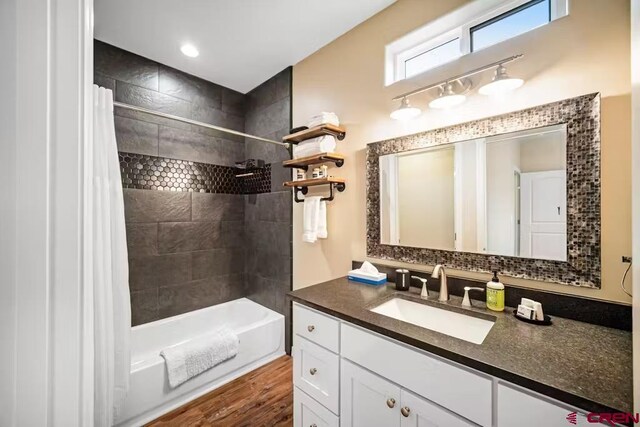 bathroom with shower / bath combo with shower curtain, wood finished floors, and vanity