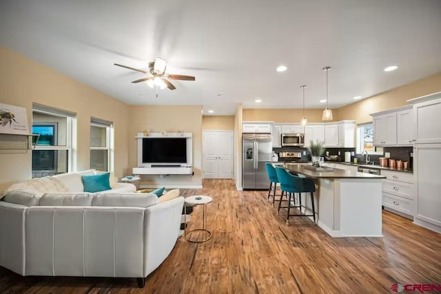 living room with a ceiling fan, recessed lighting, and wood finished floors