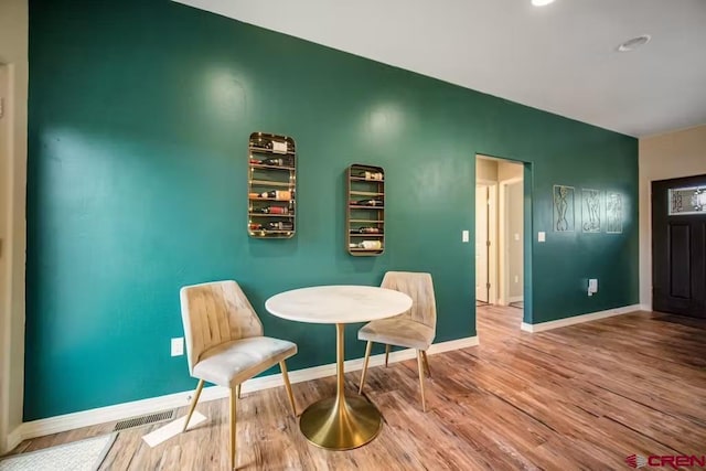 sitting room with baseboards, visible vents, and wood finished floors