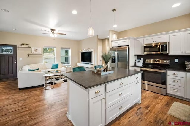 kitchen with white cabinets, ceiling fan, dark countertops, appliances with stainless steel finishes, and open floor plan