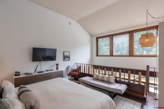 bedroom featuring a textured ceiling, wood finished floors, and vaulted ceiling