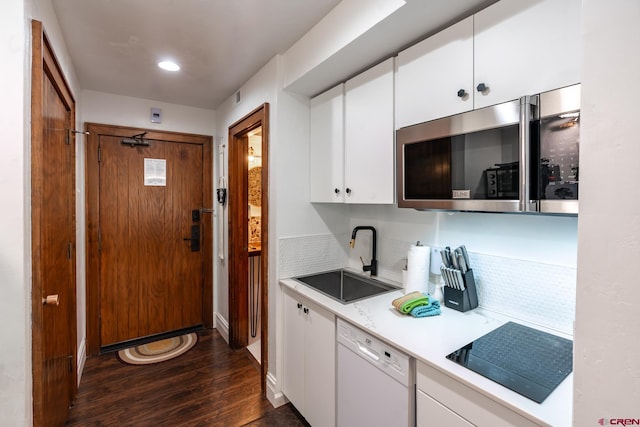 kitchen featuring a sink, dishwasher, light countertops, stainless steel microwave, and dark wood-style floors