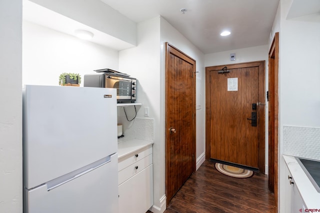 doorway featuring baseboards and dark wood-type flooring